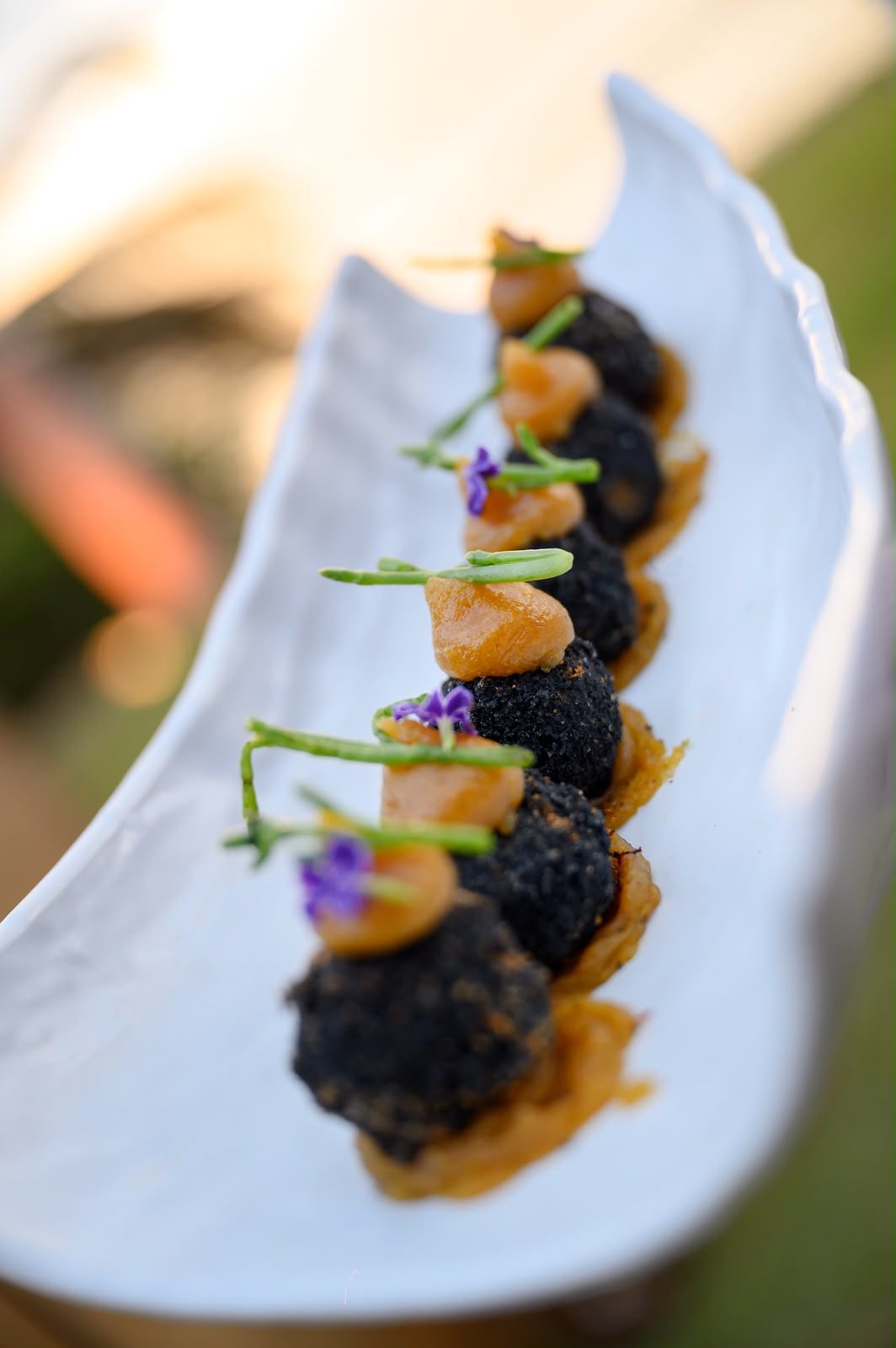 Canapés con flor violeta sobre una bandeja blanca