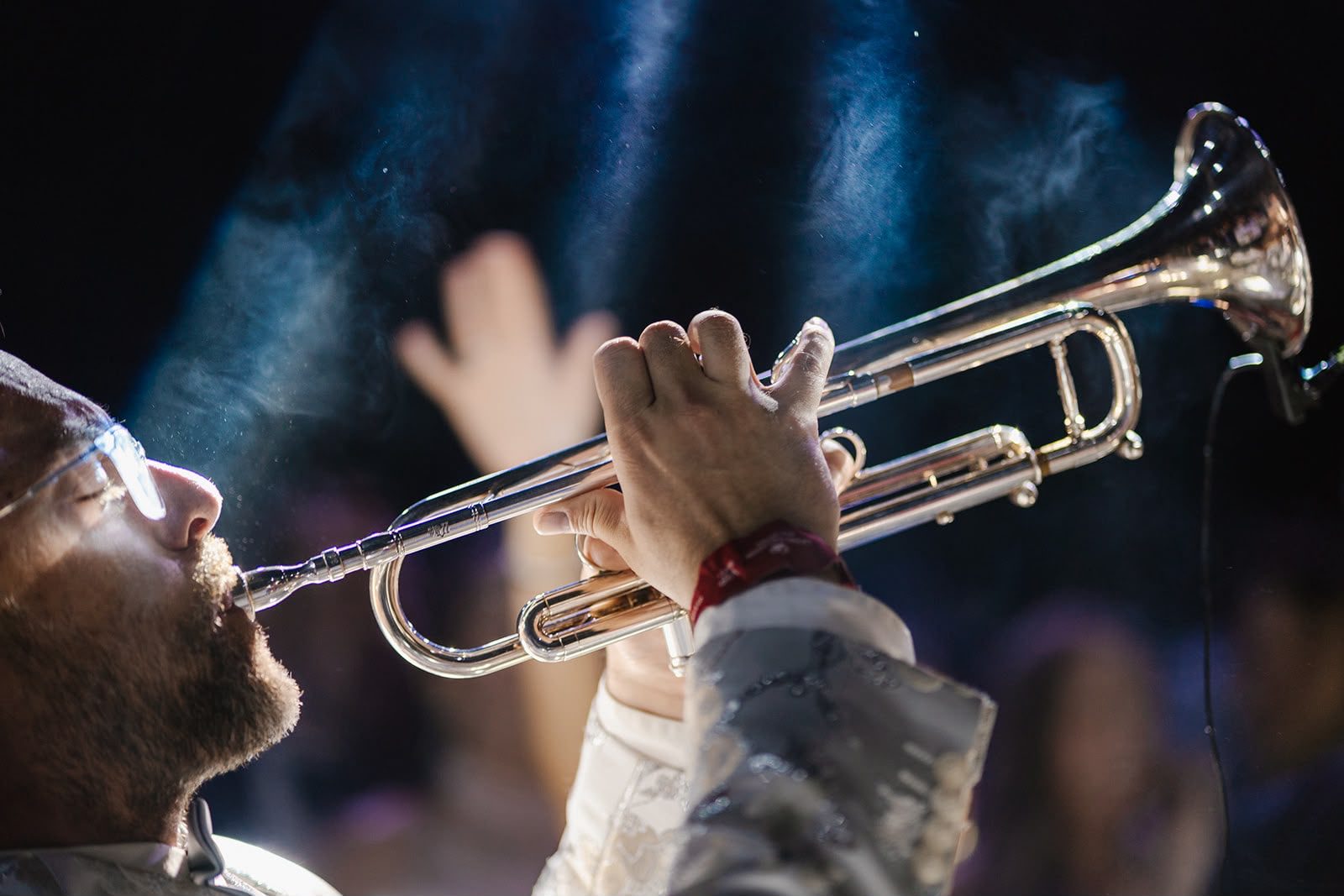 Un trompetista toca entre humo y luces durante la fiesta